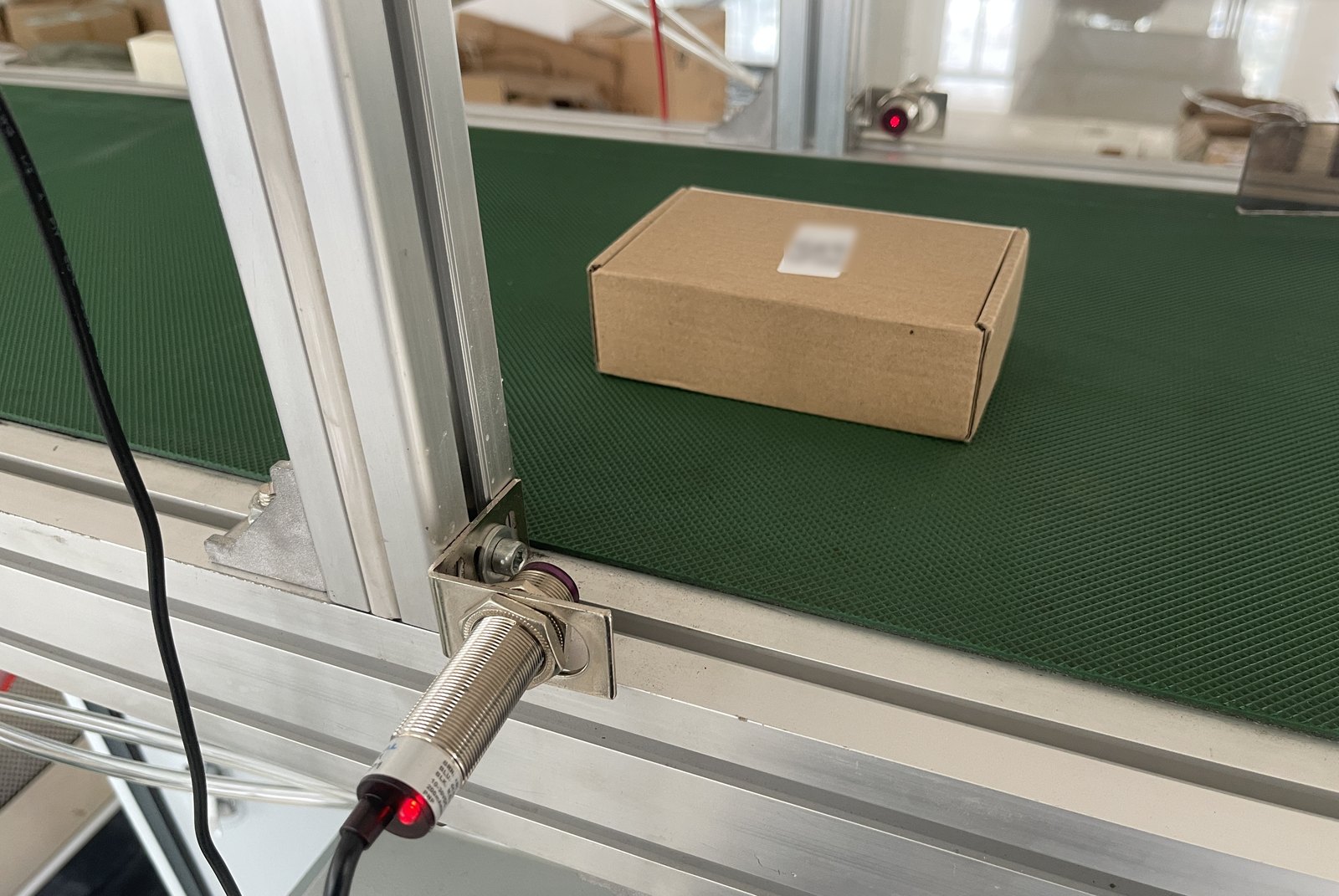 导轨上的光电传感器与传送带上贴了面单的成品包裹